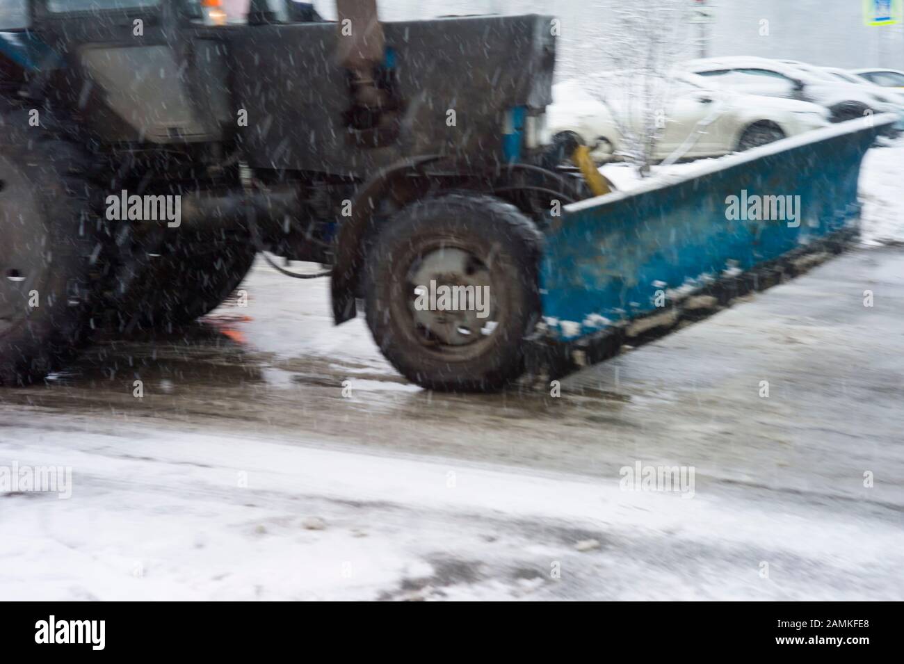 Blurred motion shot of a tractor plowing snow, urban scene Stock Photo