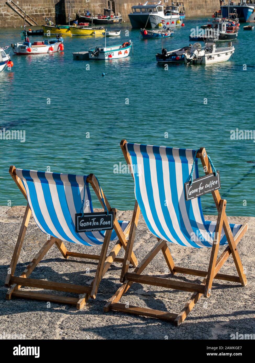 Two empty but reserved blue and white striped deckchairs with 'Gone for Tea / Coffee signs' in Summer, St. Ives Harbourside, Cornwall, England, UK Stock Photo