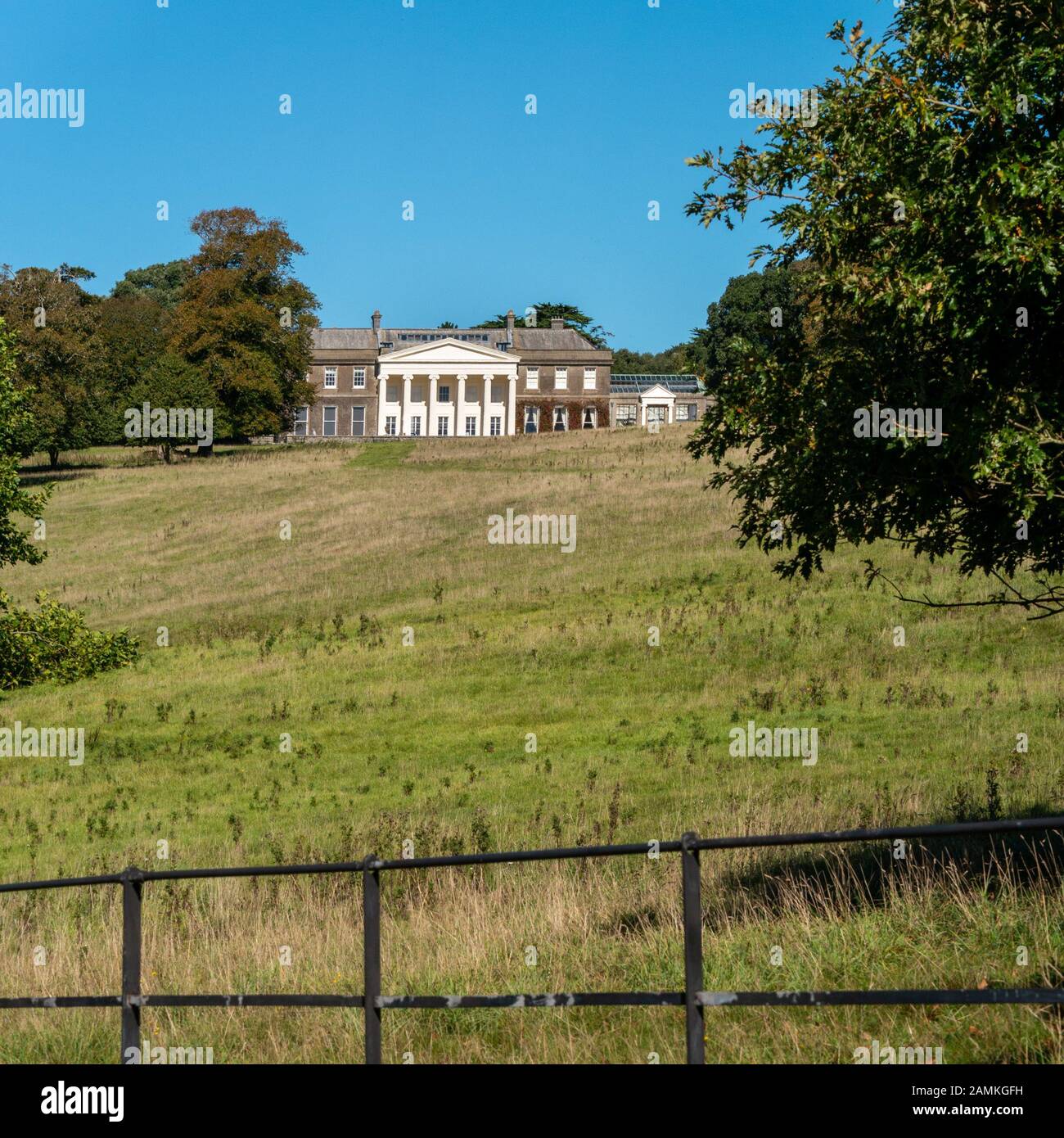 Distant view of the front of Trelissick House National Trust property with grass parkland in front with blue sky above in Summer, Cornwall, England,UK Stock Photo