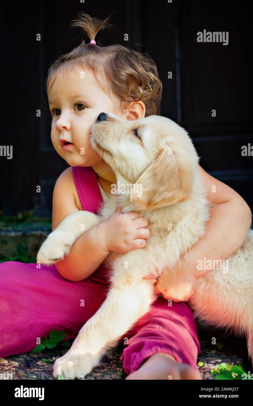 Funny photo of happy baby cuddling beautiful golden labrador retriever