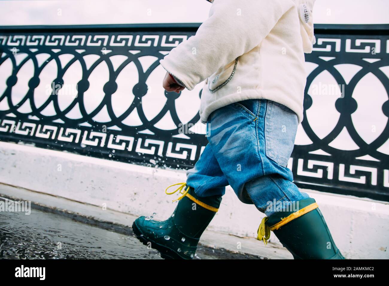 child walks through the puddles in rubber boots Stock Photo - Alamy