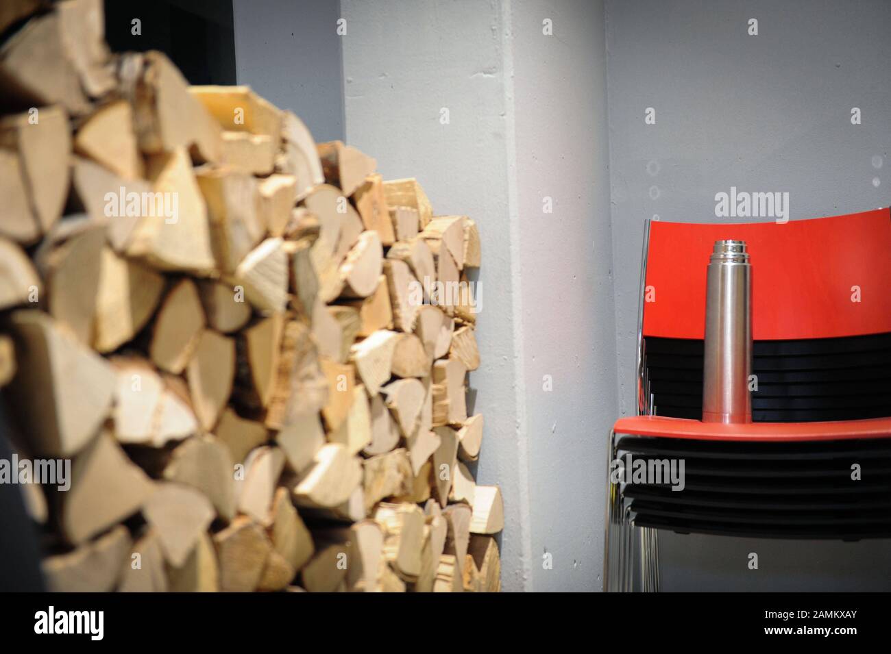 Stack with firewood and chair with thermos flask in the 'Impact Hub' in the Munich district of Sendling. The Impact Hub is intended to create a network for social, ecological entrepreneurship. [automated translation] Stock Photo