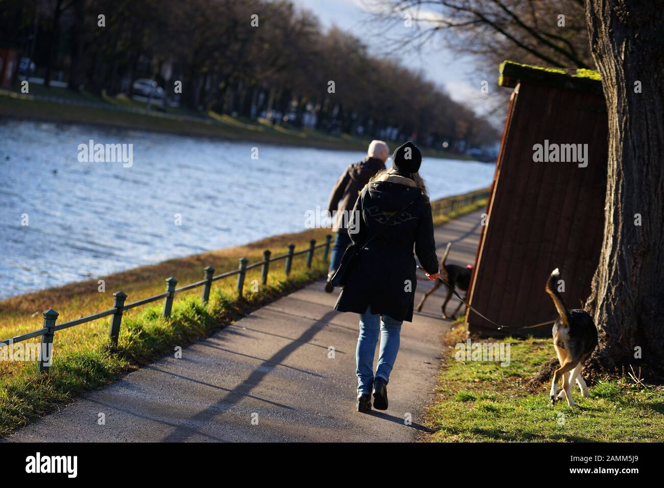 Two women are walking with their dogs on a sunny winter's day along the Nymphenburg Palace Canal. [automated translation] Stock Photo