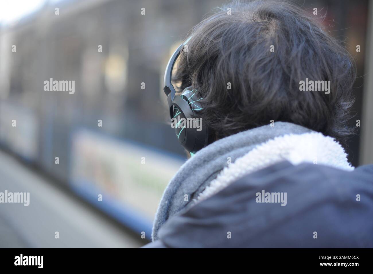 Man with headphones in front of a tram. An increasing number of pedestrians are involved in accidents due to distraction or non-perception of traffic noise caused by too loud music. [automated translation] Stock Photo