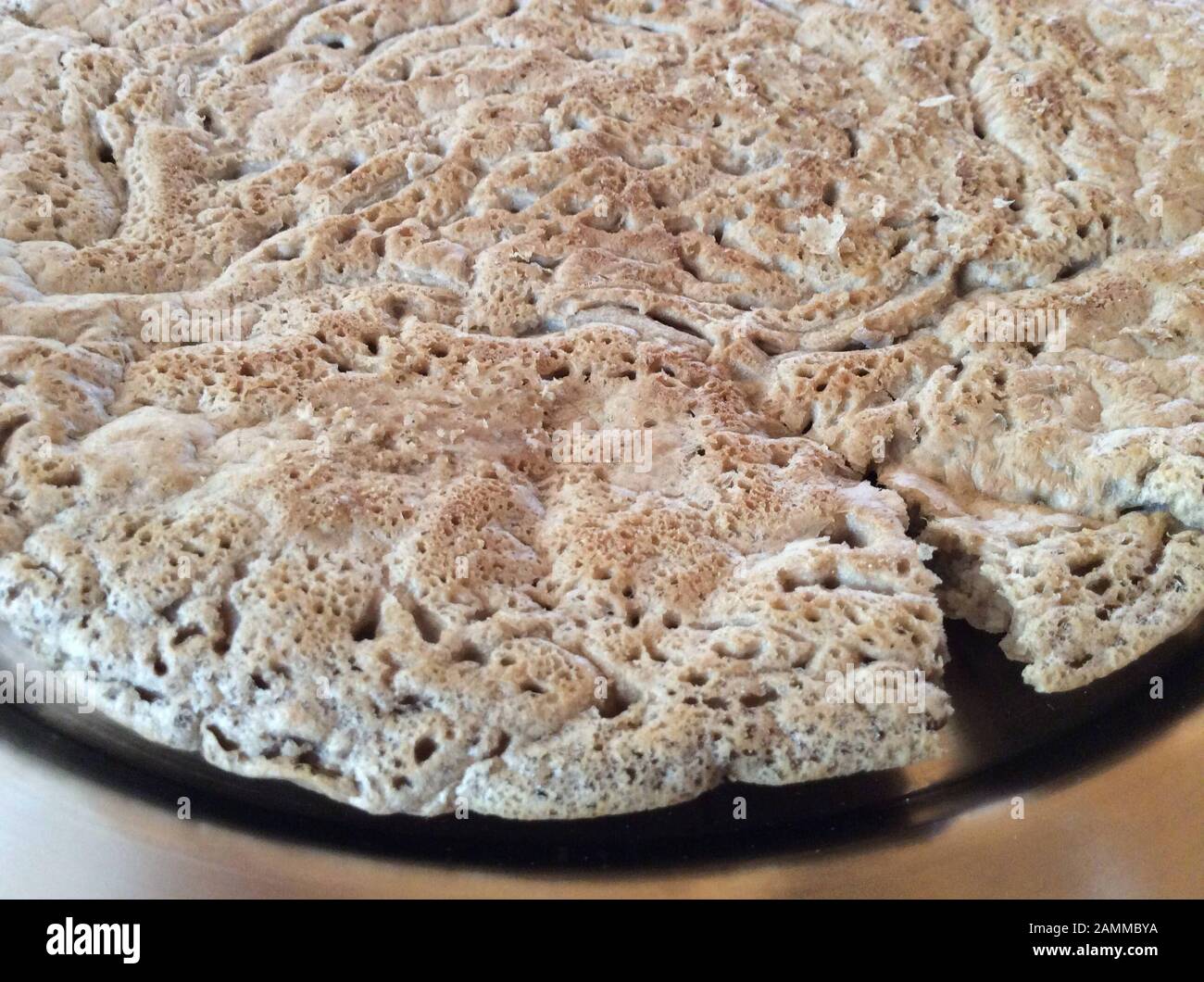 Typical sponge-like surface of an Injera bread made of teff flour and water. Teff also called dwarf millet, belongs to the sweet grass family. The natural range is in Ethiopia and Eritrea, but the species is also cultivated in other tropical and subtropical areas. The seeds are gluten-free and rich in essential fatty acids. This type of millet is the most important grain in Ethiopia. It is processed there into flat bread and beer or is also used as animal feed [automated translation] Stock Photo