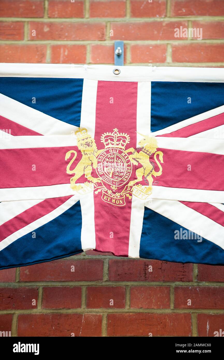 LONDON - JUNE 2012: British Union Jack flag with the royal coat of arms in gold flies against a brick wall. Stock Photo