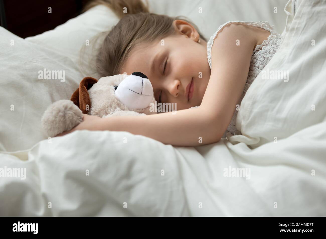 Cute little girl, peaceful child sleeping in bed, hugging toy Stock Photo