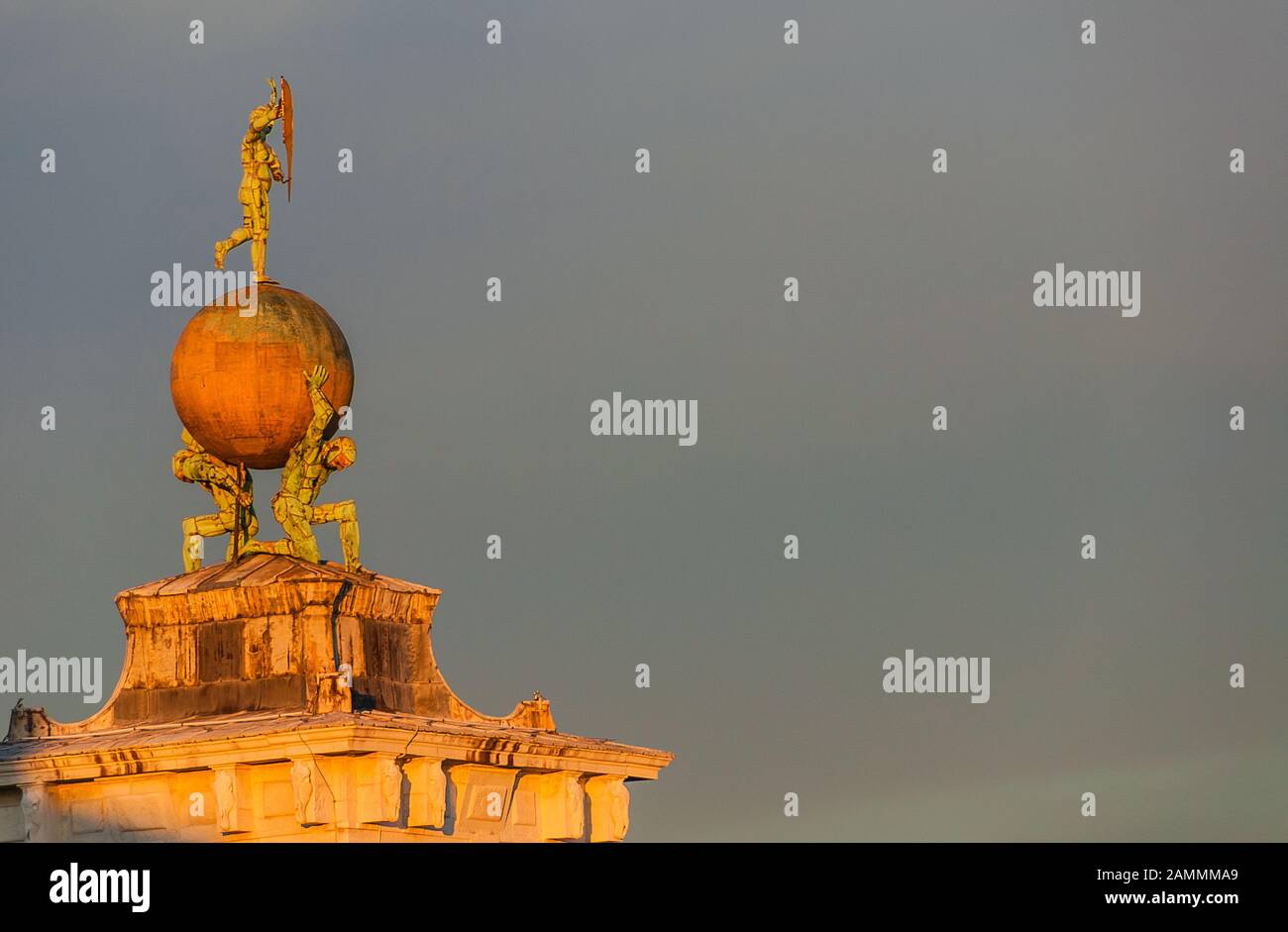 Sunset view of Fortune goddess statue with two atlas and golden globe at the top of Old Customs House in Venice, made in the 17th century by italian a Stock Photo
