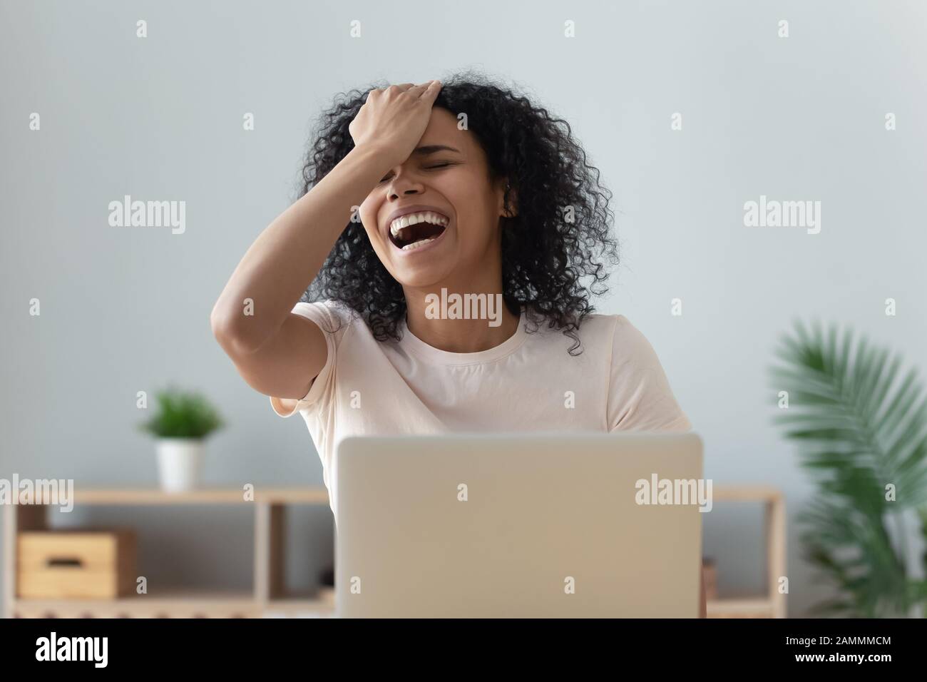 African woman laughing watching on pc very funny movie Stock Photo