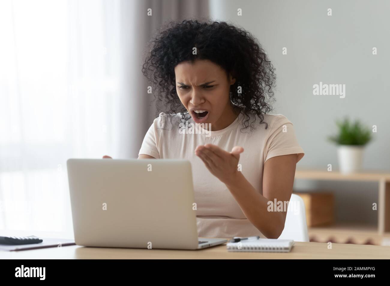 Irritated woman swears at broken or hanging out computer Stock Photo
