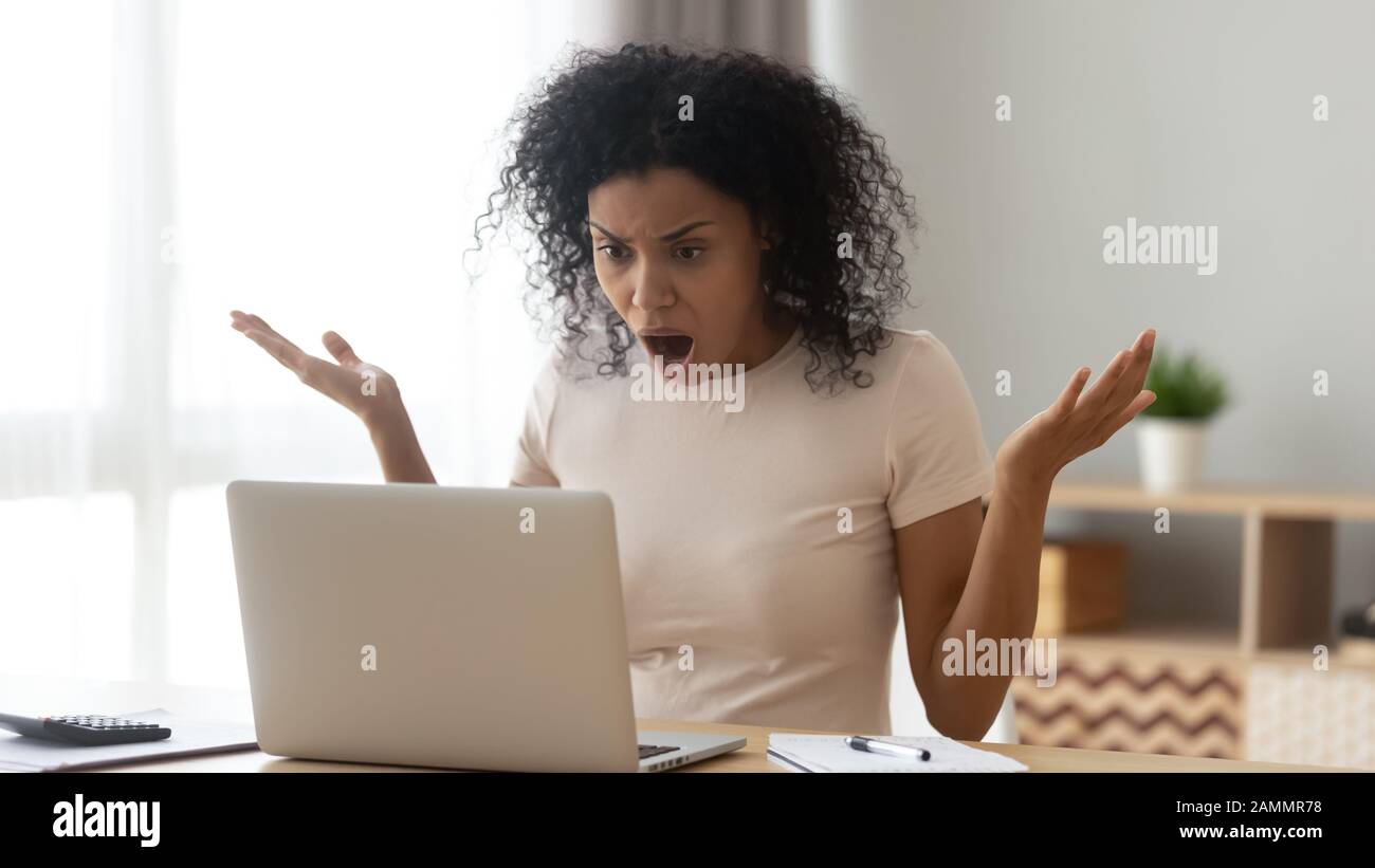 Amazed shocked african woman open mouth gawp at computer screen Stock Photo