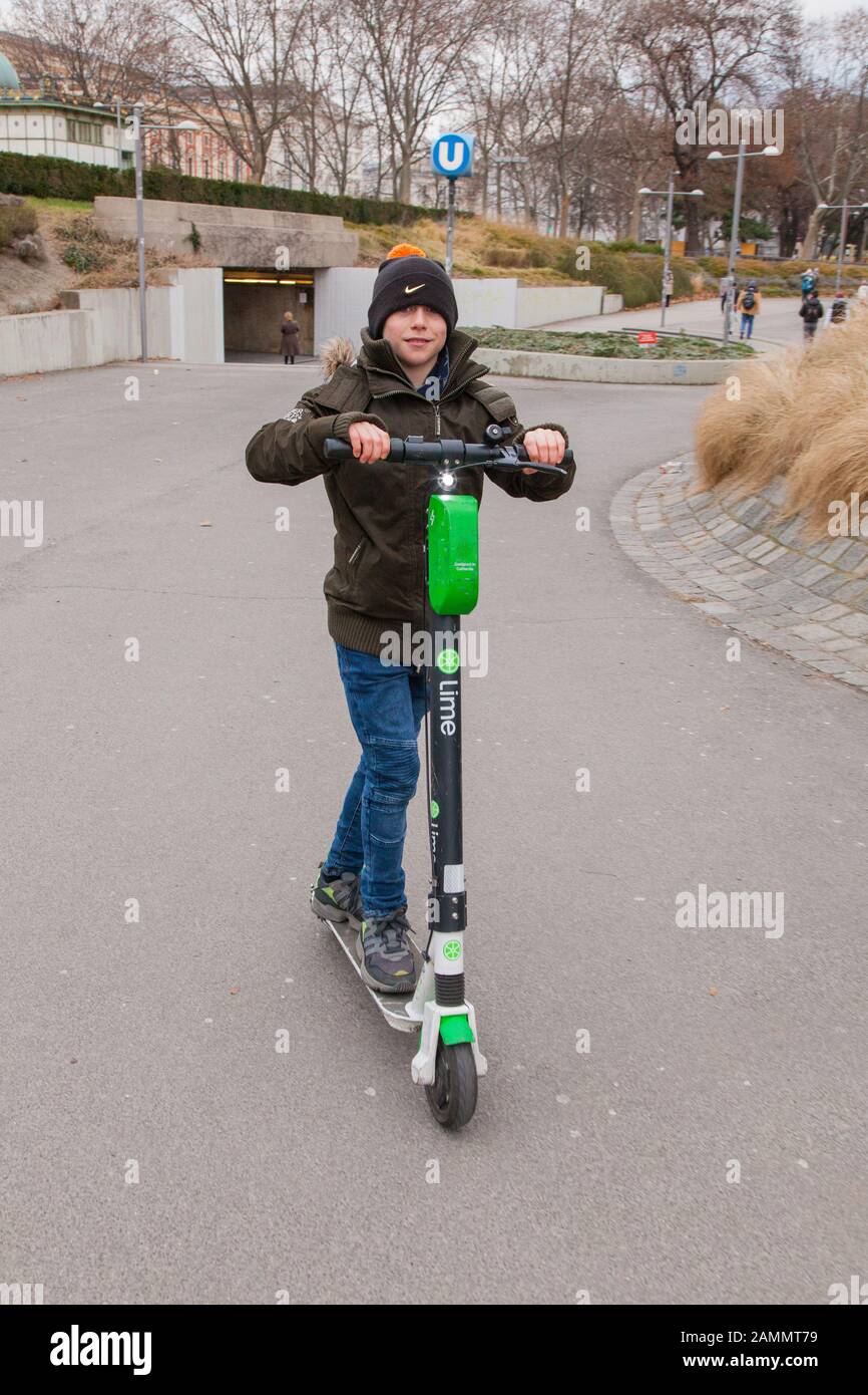 Ten year old boy riding a electric Lime hire scooter, Karlsplatz, Vienna, Austria. Stock Photo