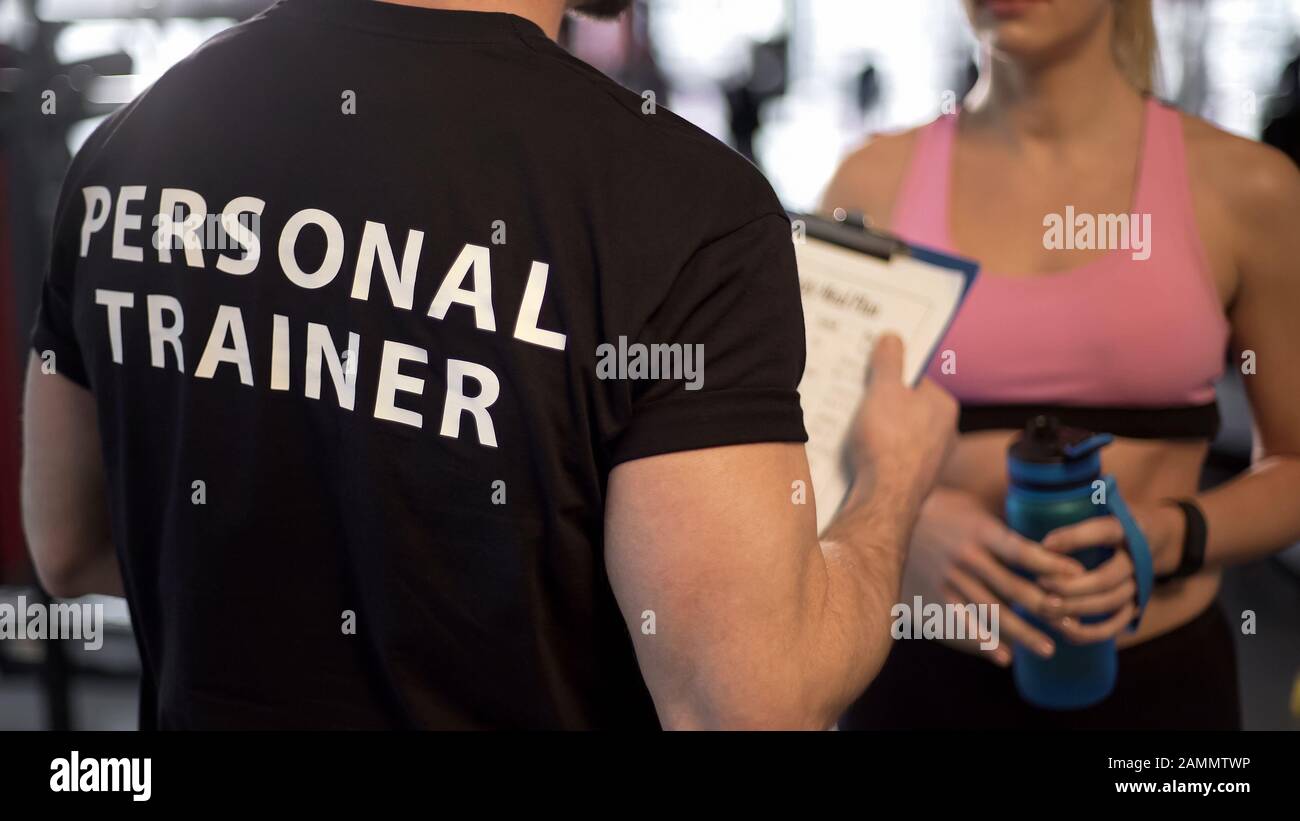 Fitness coach explaining training program and schedule to female client ...