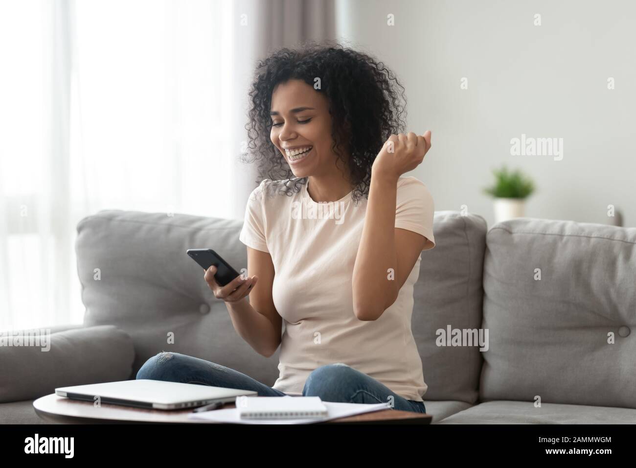 African overjoyed woman holding smartphone looking at screen ...
