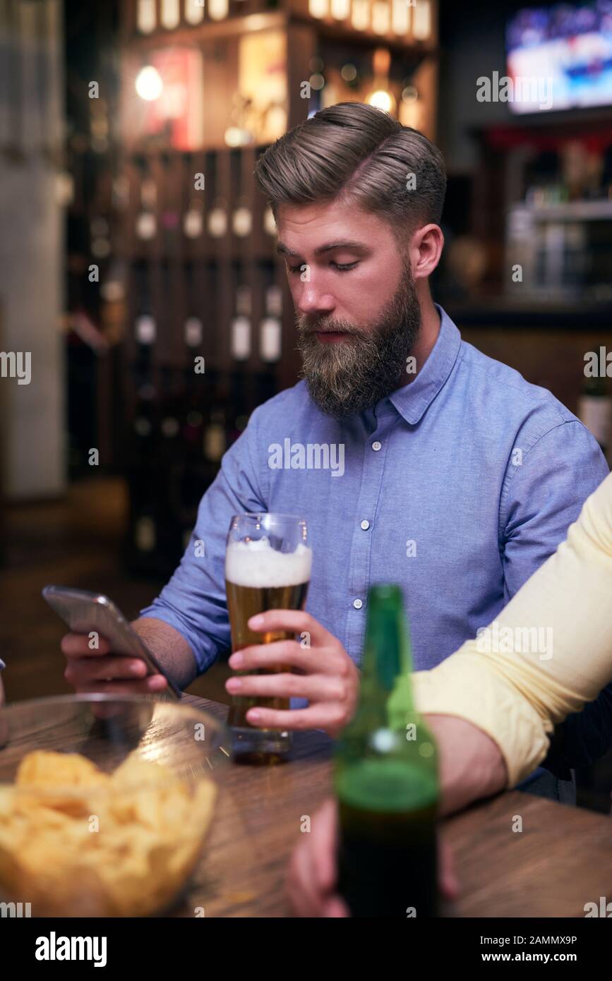 Hipster man using mobile phone and drinking beer Stock Photo