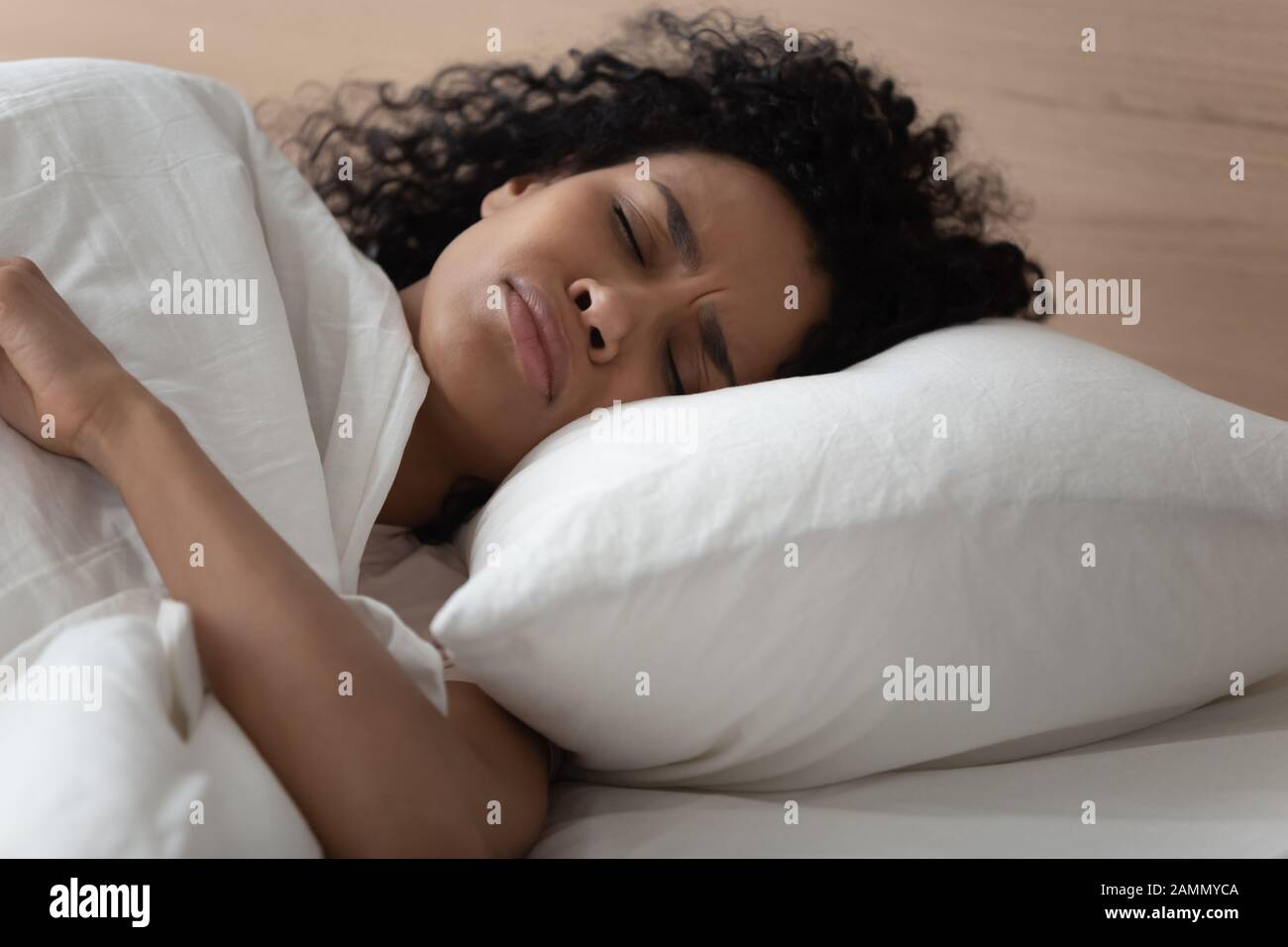 African woman lying in bed has nightmares sleeps bad Stock Photo