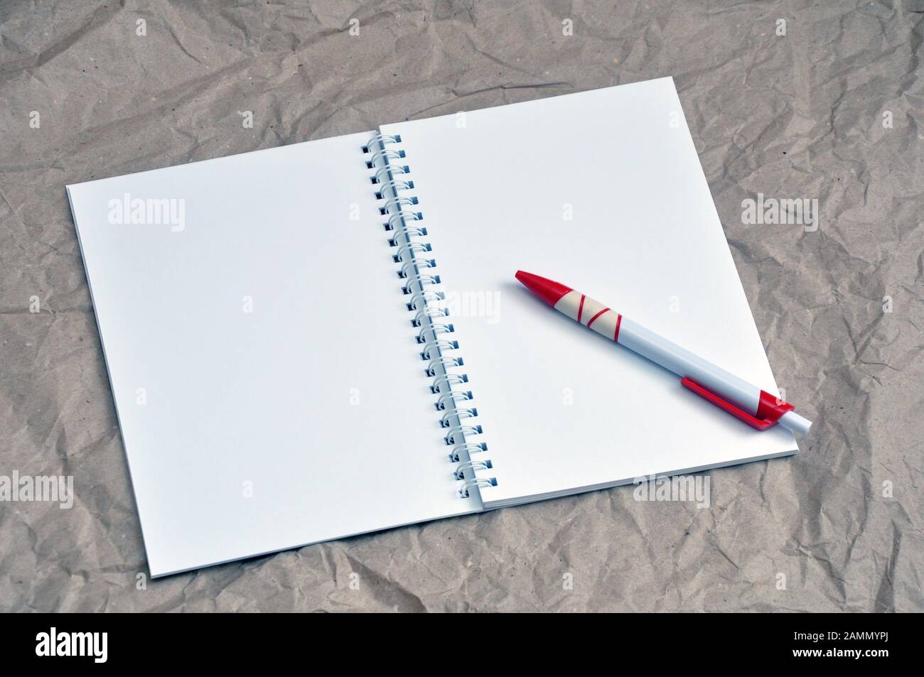 A pen on a blank notebook on a background of crumpled beige packaging. Stock Photo