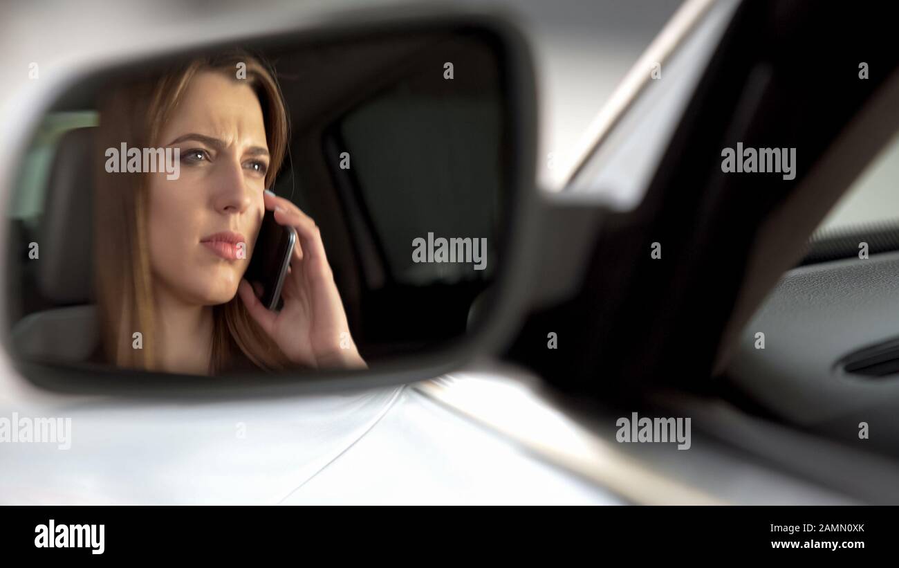 Woman talking on phone while driving, inattentive on road, rearview mirror Stock Photo