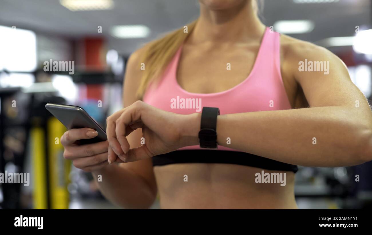 Lady checking training progress using fitness bracelet and mobile application Stock Photo