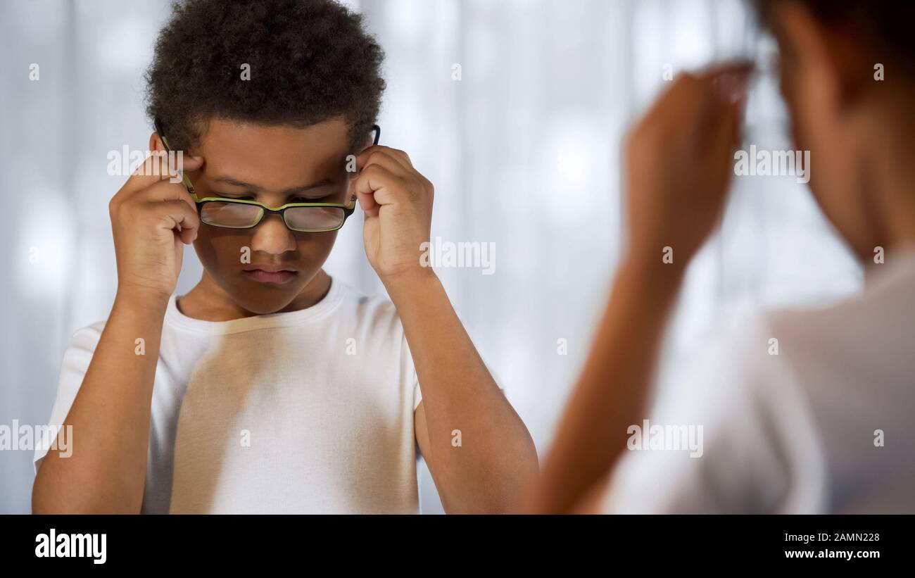Sad child trying on eyeglasses, appearance insecurities, far-sightedness, health Stock Photo
