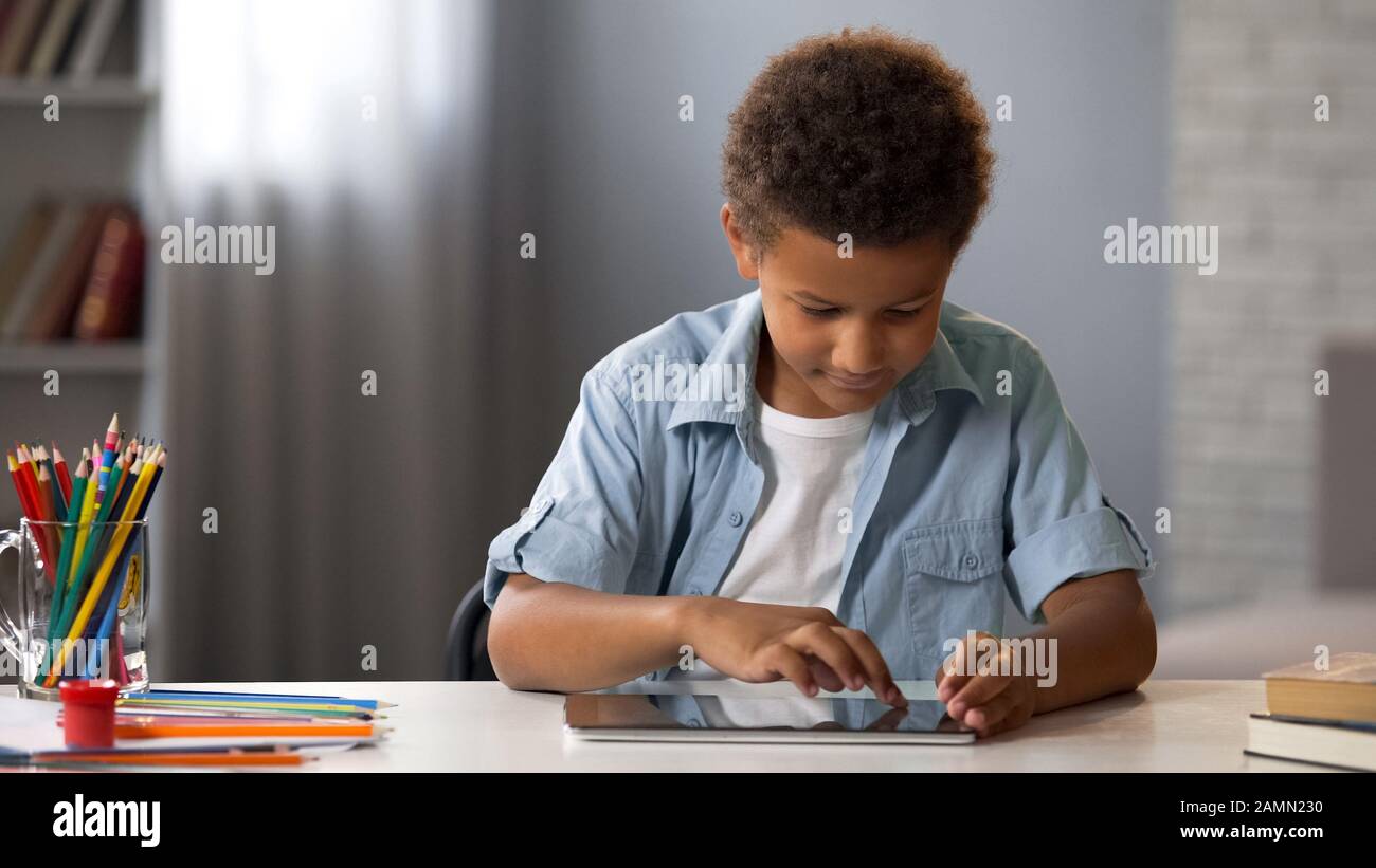 Little clever kid swiping tablet playing in interactive educational application Stock Photo