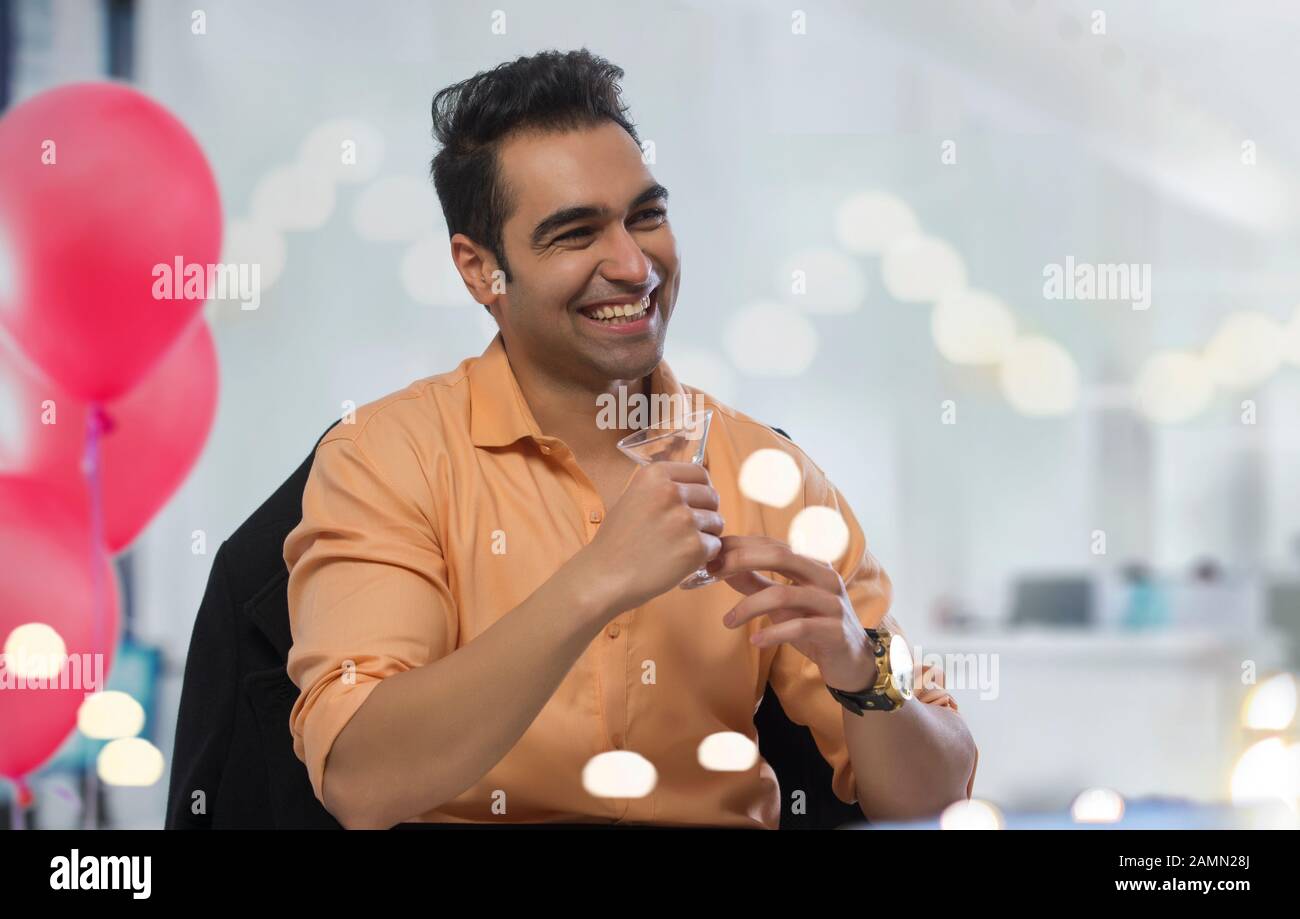 Young man having a drink at his office party. Stock Photo