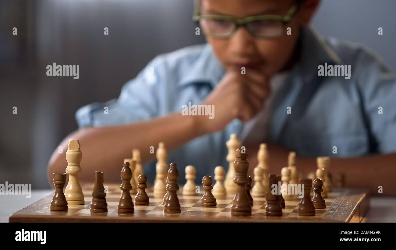 Premium Photo  Young white child playing a game of chess on large chess  board chess board on table in front of school boy thinking of next move