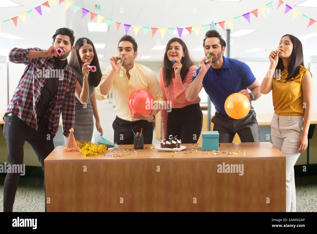 Group of colleagues blowing party hooters during a celebration in office. Stock Photo