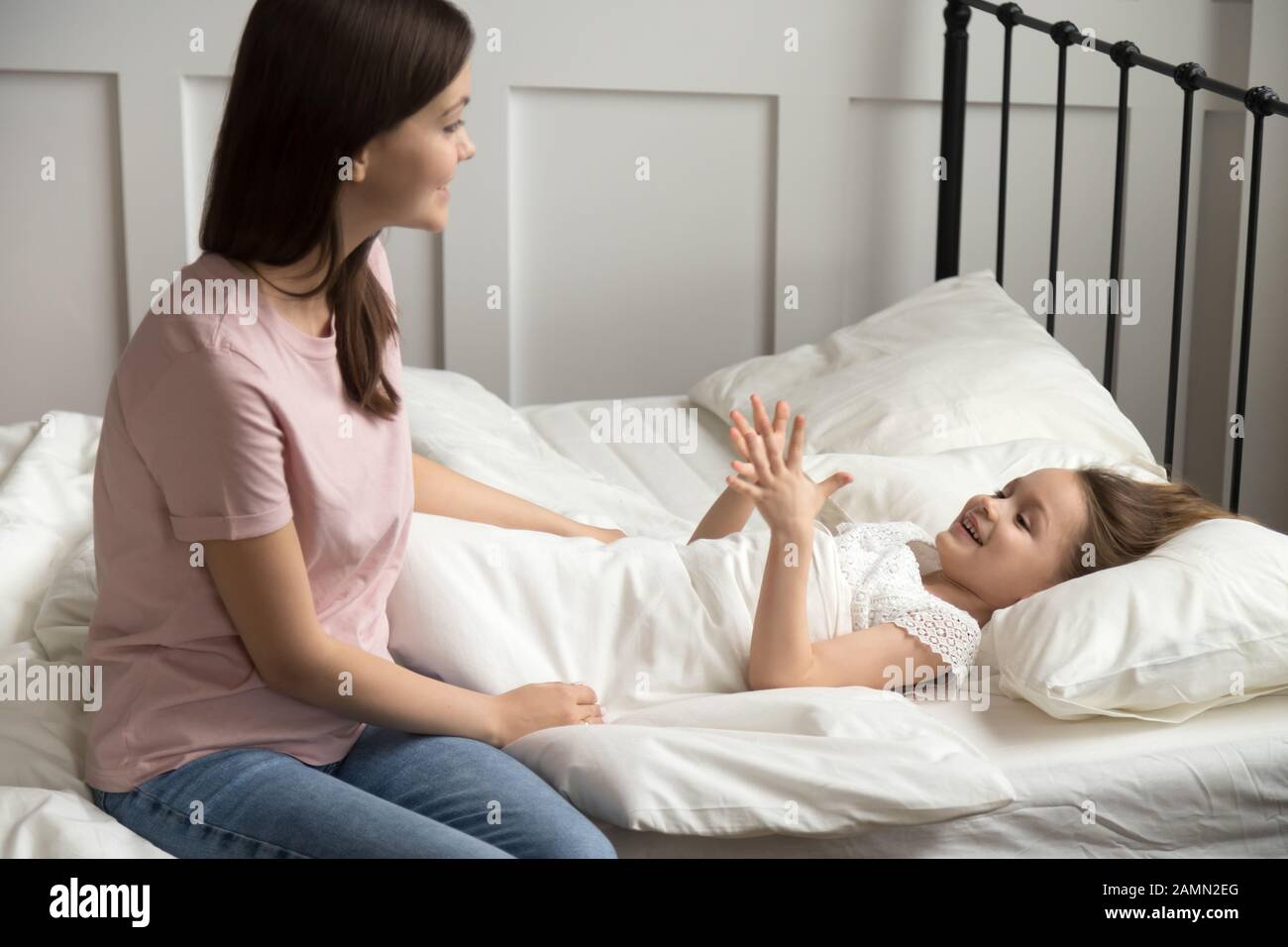 Loving mother puts adorable little daughter to sleep, telling story Stock Photo