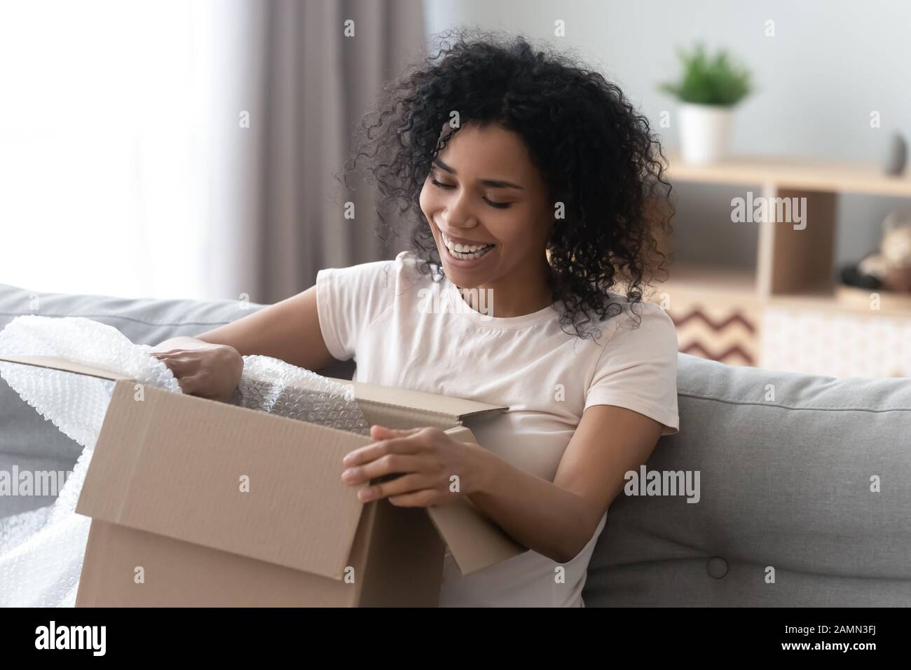 African woman unpacking cardboard box parcel feels happy Stock Photo