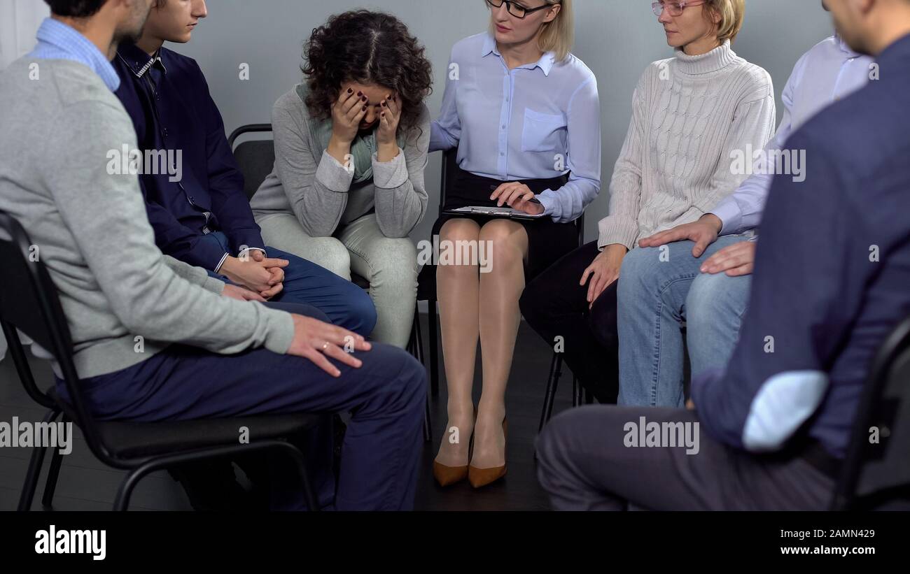 Woman crying at therapy session, female psychotherapist comforting her