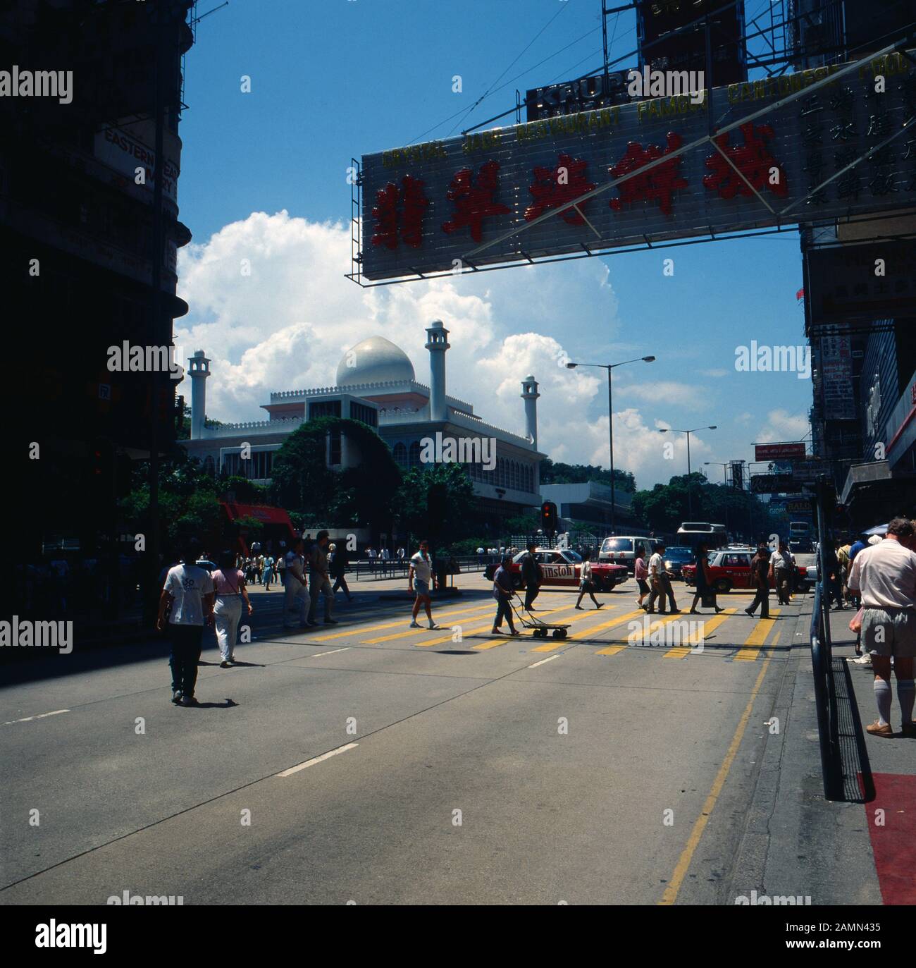 Menschen auf einer Straßenkreuzung vor der Kowloon Moschee, Hongkong 1980er Jahre. People crossing the streets in front of Kowloon Mosque at Hong Kong, 1980s. Stock Photo
