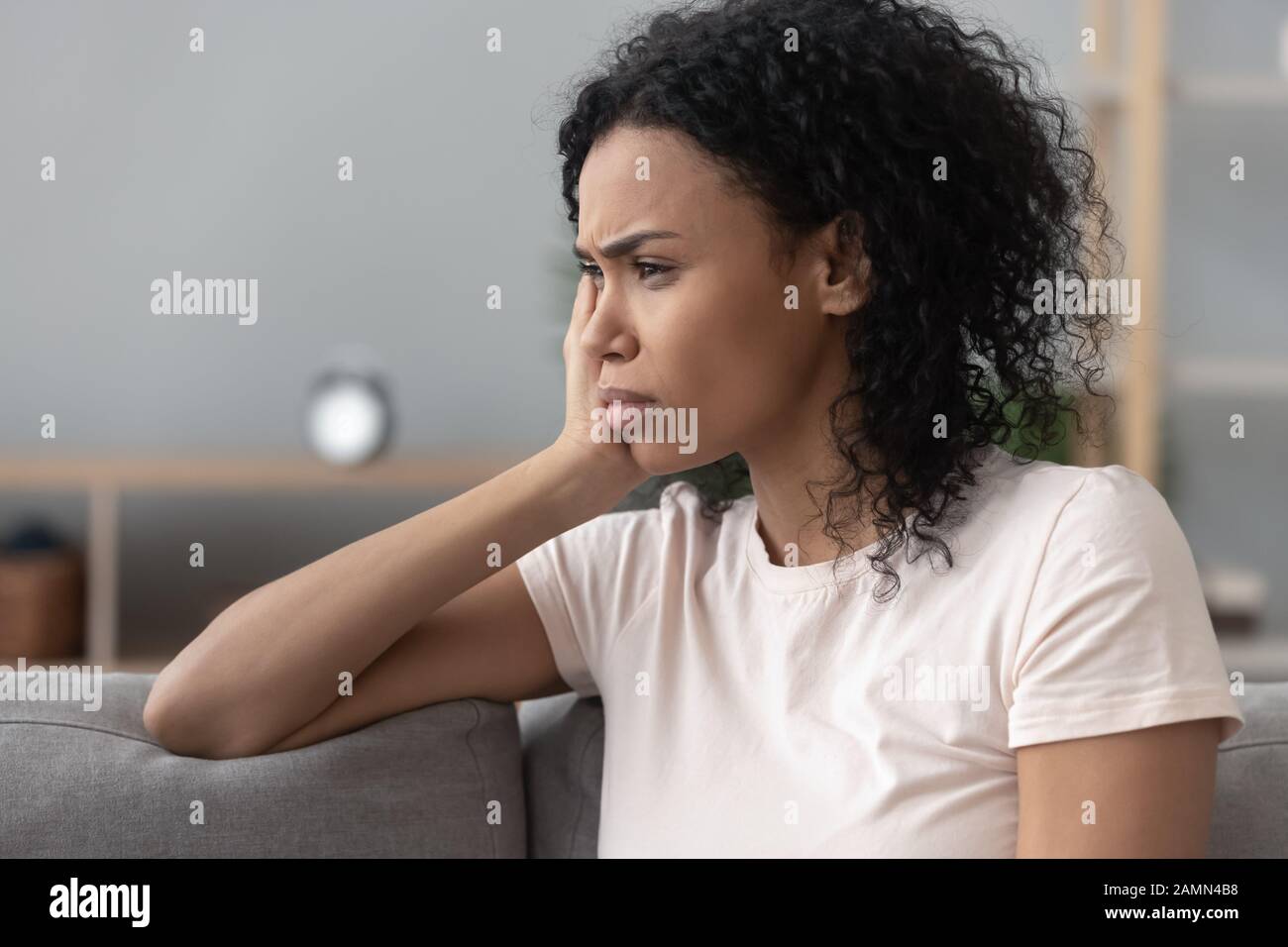 Side closeup view african sad pensive woman sitting on couch Stock Photo