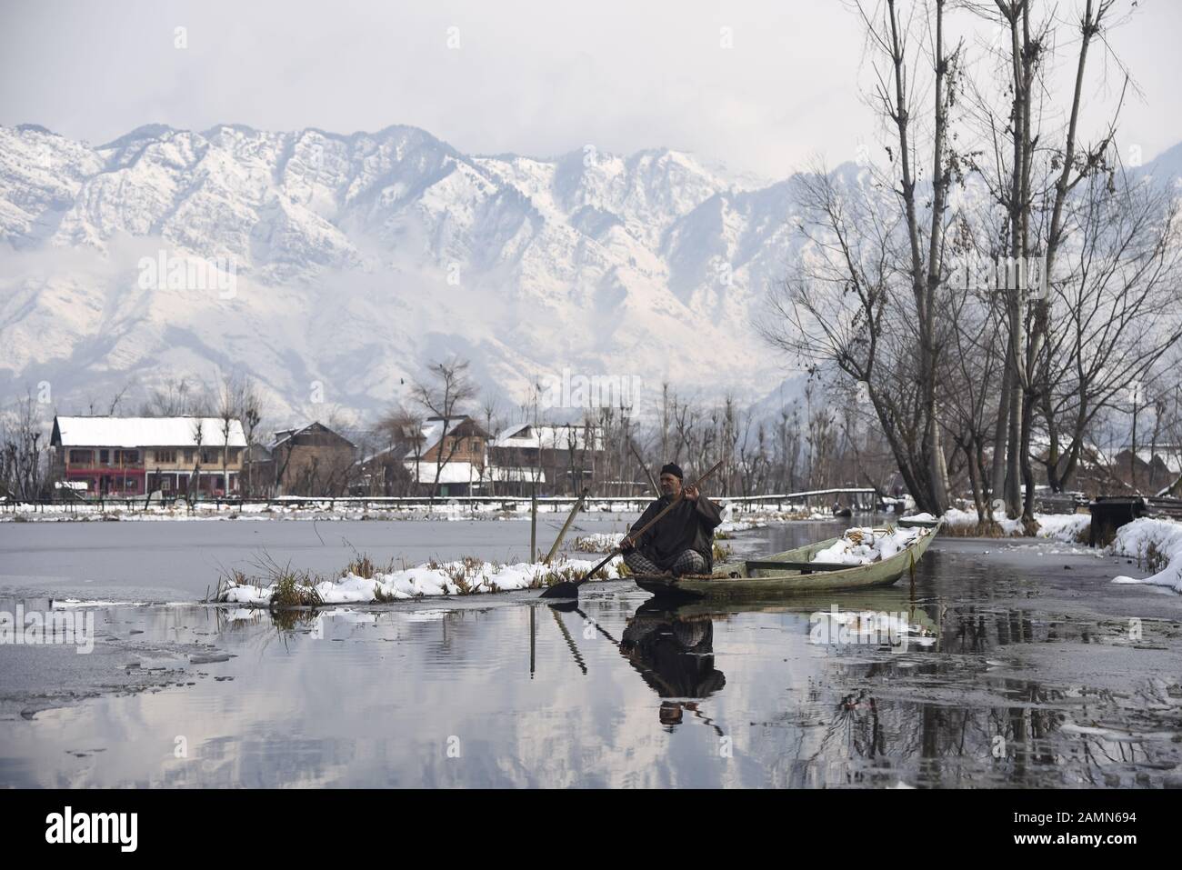 A Kashmiri boatman rows his boat on Dal Lake after fresh snowfall in Srinagar.Due to heavy snowfall in the last 48 hours, there have been multiple avalanches in which at least 4 Indian army soldiers and 5 civilians Killed in the Indian administered Kashmir. Stock Photo