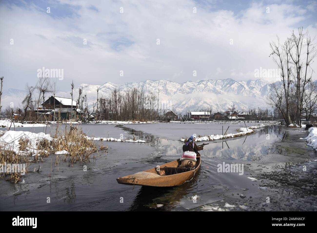 A Kashmiri woman rows her boat on Dal Lake after fresh snowfall in Srinagar.Due to heavy snowfall in the last 48 hours, there have been multiple avalanches in which at least 4 Indian army soldiers and 5 civilians Killed in the Indian administered Kashmir. Stock Photo