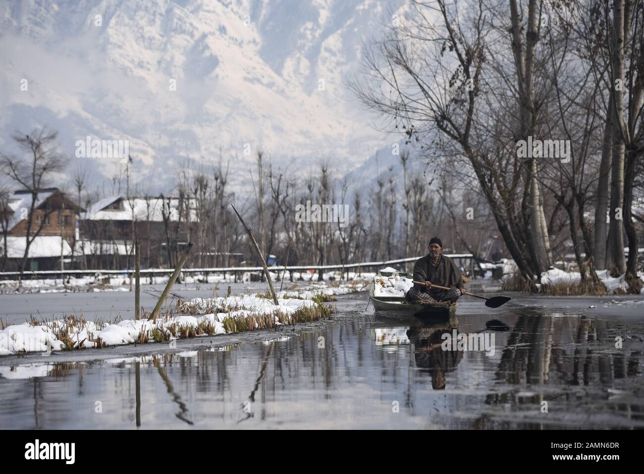 A Kashmiri boatman rows his boat on Dal Lake after fresh snowfall in Srinagar.Due to heavy snowfall in the last 48 hours, there have been multiple avalanches in which at least 4 Indian army soldiers and 5 civilians Killed in the Indian administered Kashmir. Stock Photo