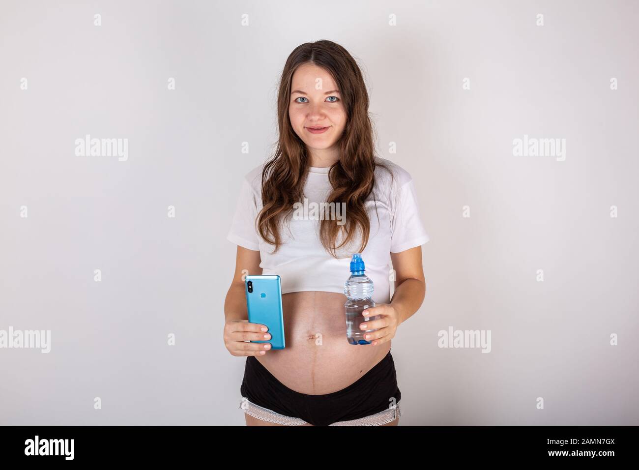 beautiful pregnant woman drinking water from the bottle on