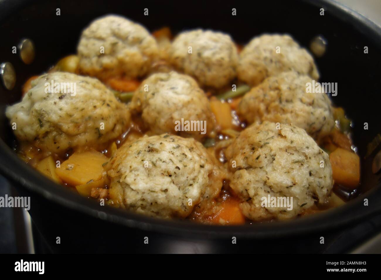 Large Black Pan Of Homemade Vegetable Broth Eight Herby Dumplings Cooking On A Gas Hob Stock Photo Alamy