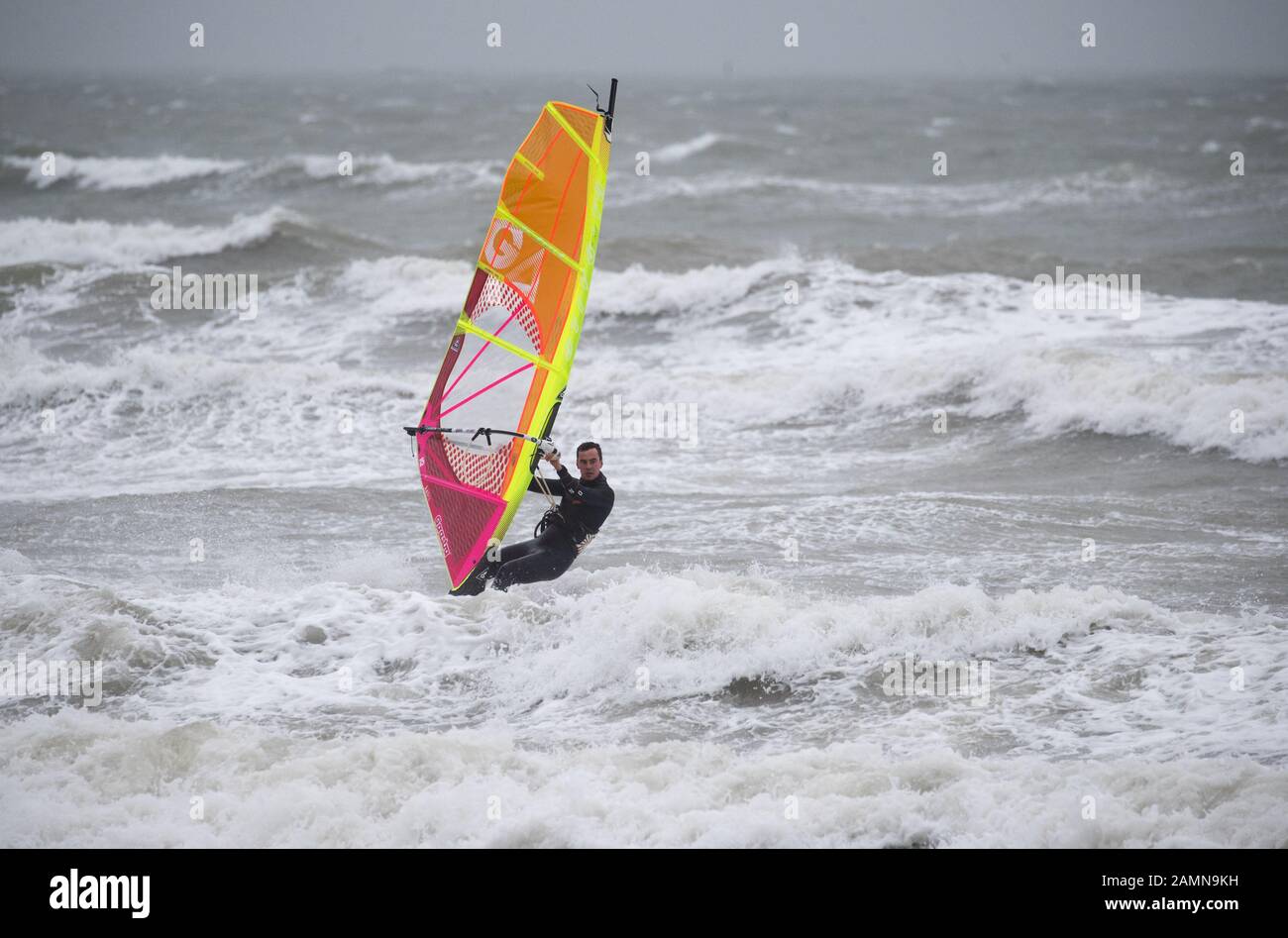 A windsurfer enjoys the strong winds in the sea off of Preston beach near Weymouth in Dorset. Stock Photo