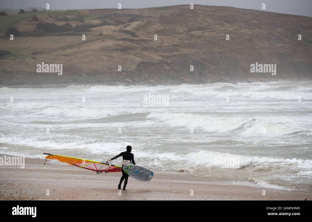 A windsurfer enjoys the strong winds in the sea off of Preston beach near Weymouth in Dorset. Stock Photo