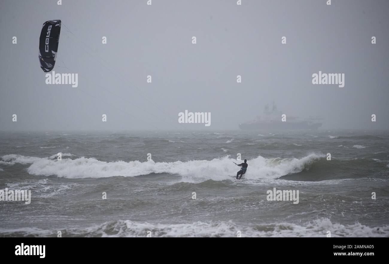 A kitesurfer enjoys the strong winds in the sea off of Preston beach near Weymouth in Dorset. Stock Photo