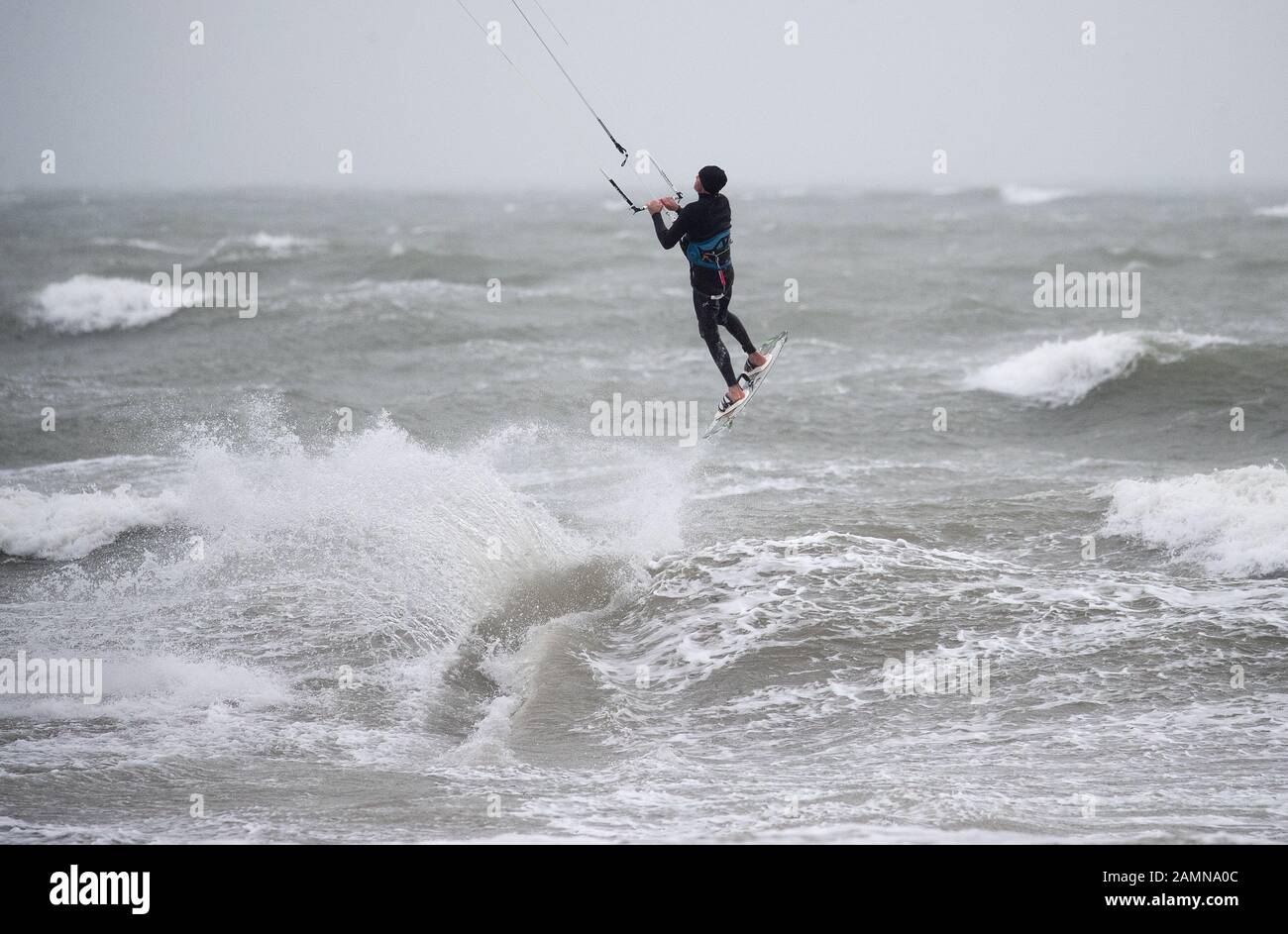 A kitesurfer enjoys the strong winds in the sea off of Preston beach near Weymouth in Dorset. Stock Photo