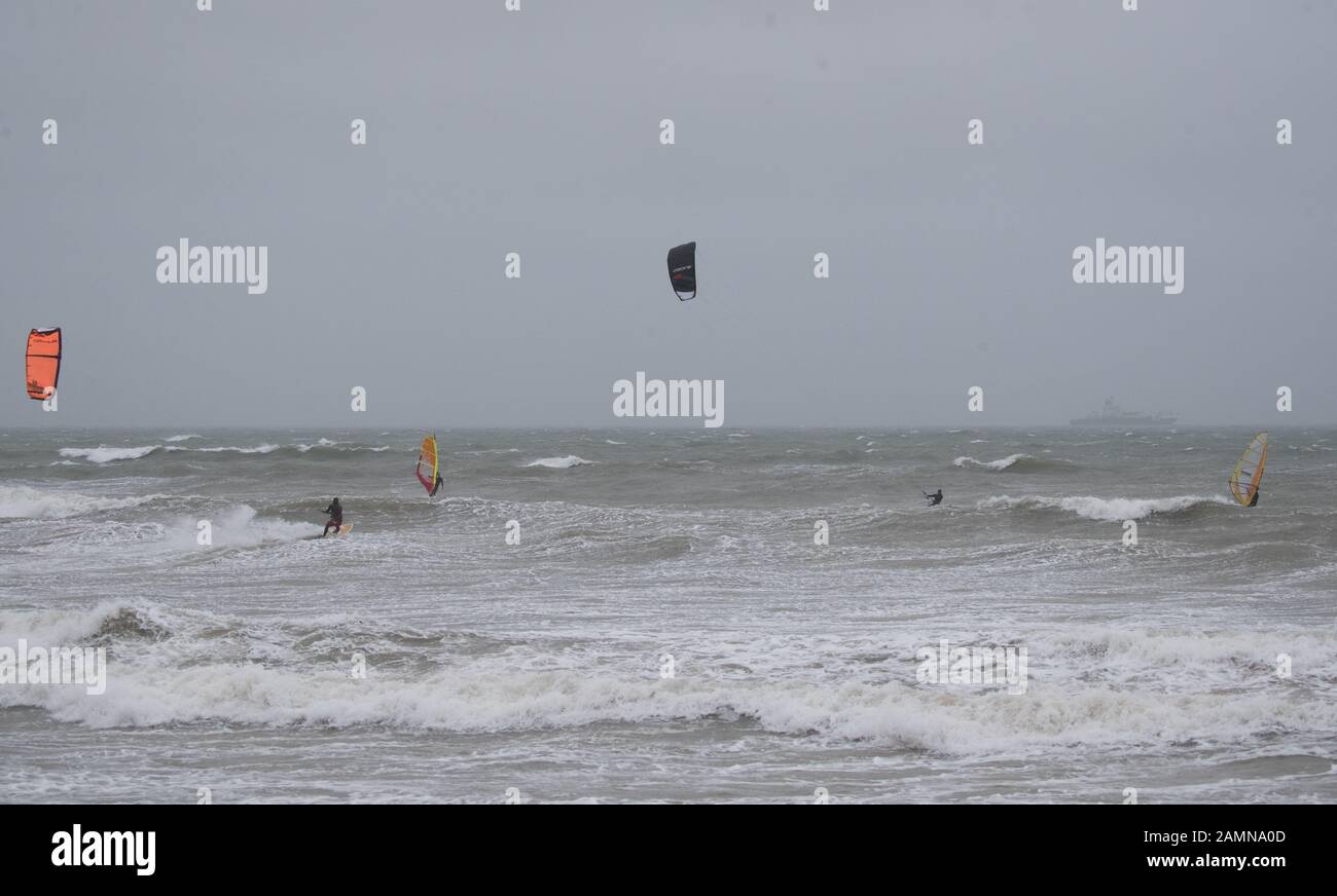 Windsurfers and kite surfers enjoy the strong winds in the sea off of Preston beach near Weymouth in Dorset. Stock Photo