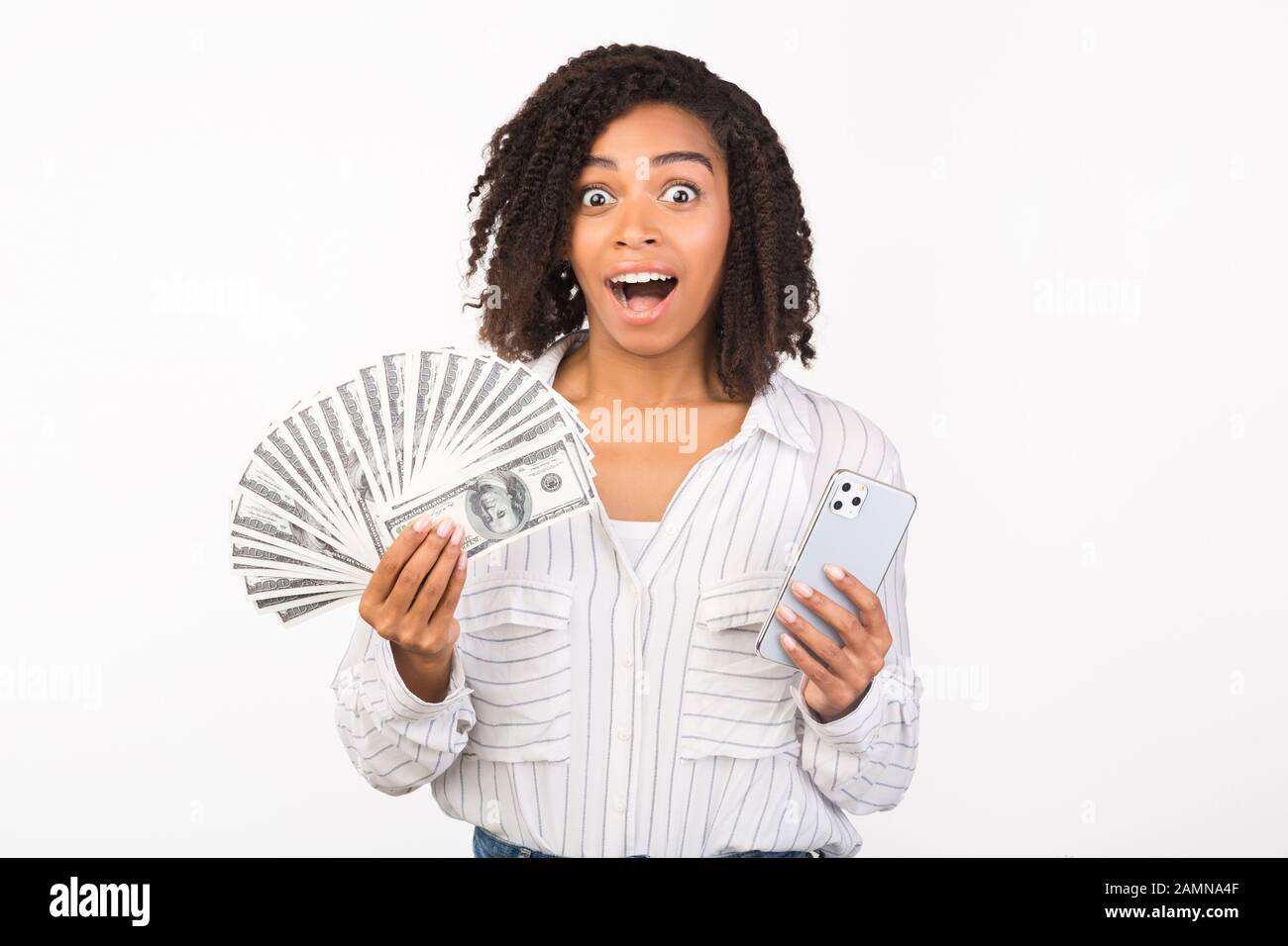 Excited black woman holding money and iPhone 11 Stock Photo