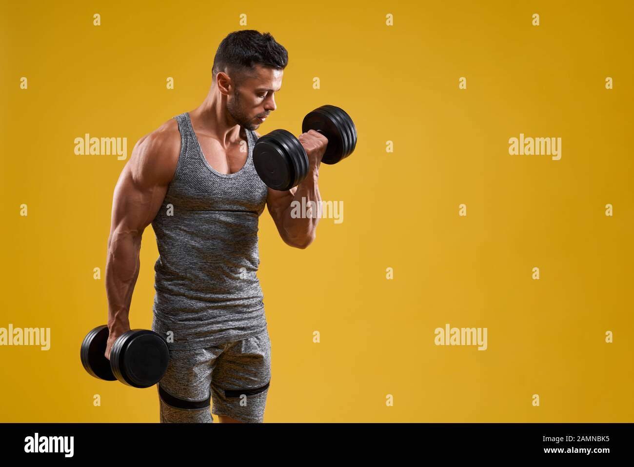 Side view of handsome athletic bodybuilder lifting heavy weight. Strong  brutal guy in sportswear pumping up muscles. Isolated on yellow studio  background with copy space. Concept of sport Stock Photo - Alamy