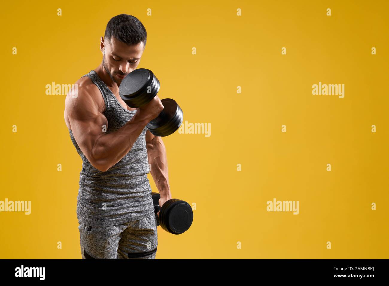 Premium Photo  Young male bodybuilder doing heavy weight exercise with  dumbbells against dark background