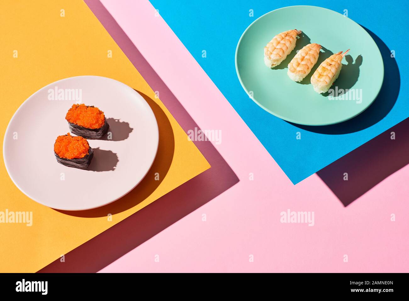 fresh nigiri with shrimps and red caviar on blue, pink, orange background Stock Photo