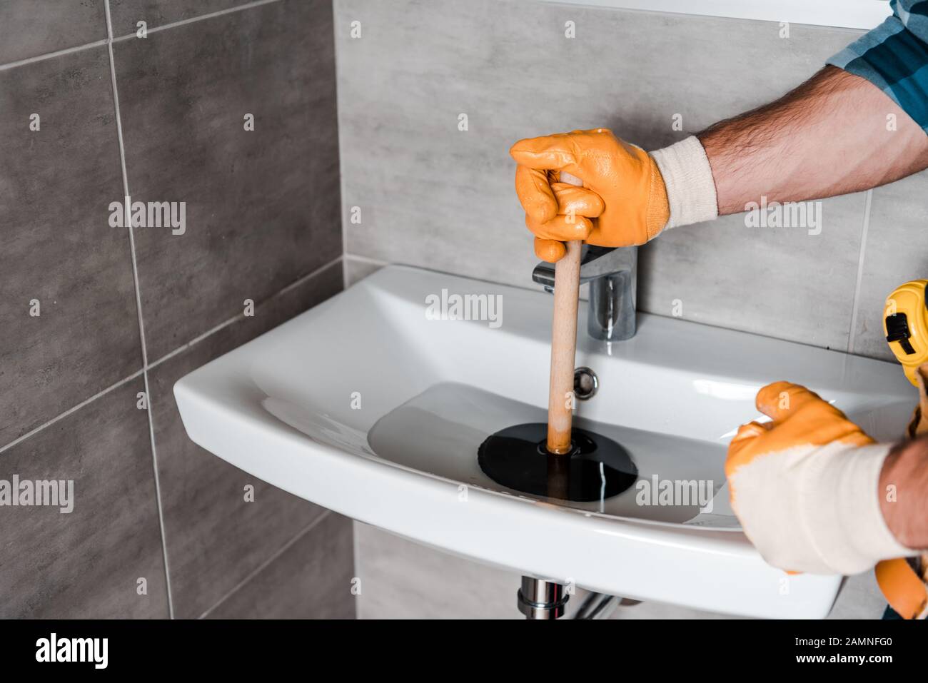 https://c8.alamy.com/comp/2AMNFG0/cropped-view-of-man-holding-plunger-in-sink-with-water-2AMNFG0.jpg