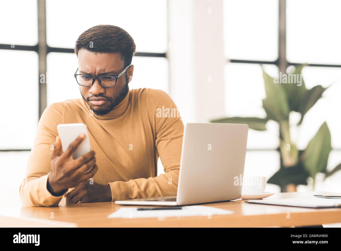 Surprised young afro manager looking at his cellphone Stock Photo
