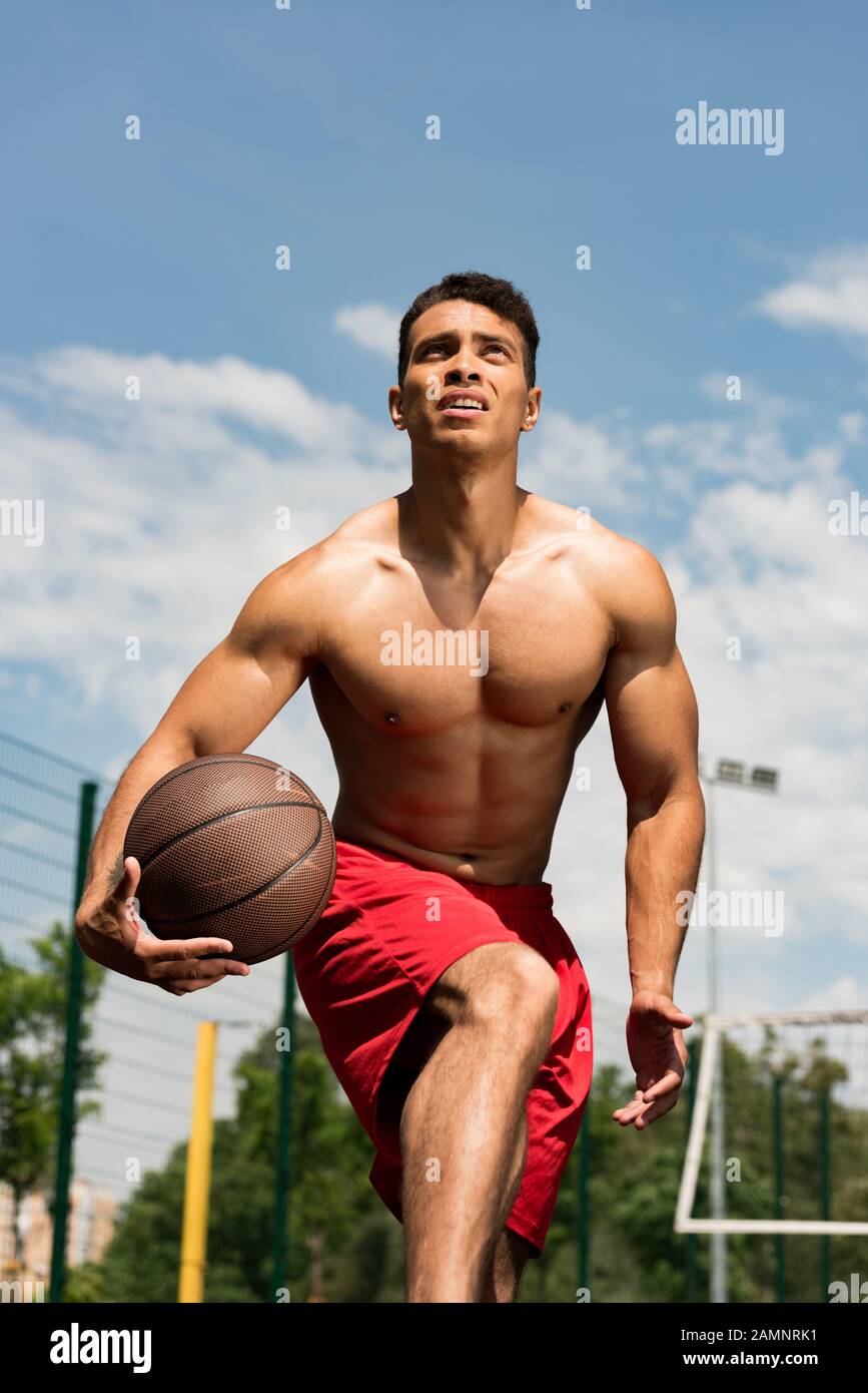 focused shirtless mixed race basketball player with ball at basketball ...